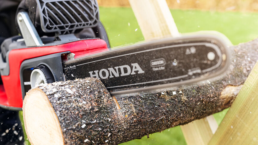 Nahaufnahme eines Modells, das mit einer Honda-Akku-Kettensäge Holz schneidet.