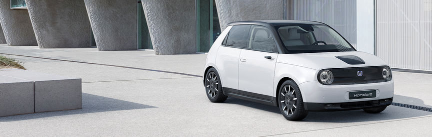 Honda e, geparkt vor einem Geb&auml;ude