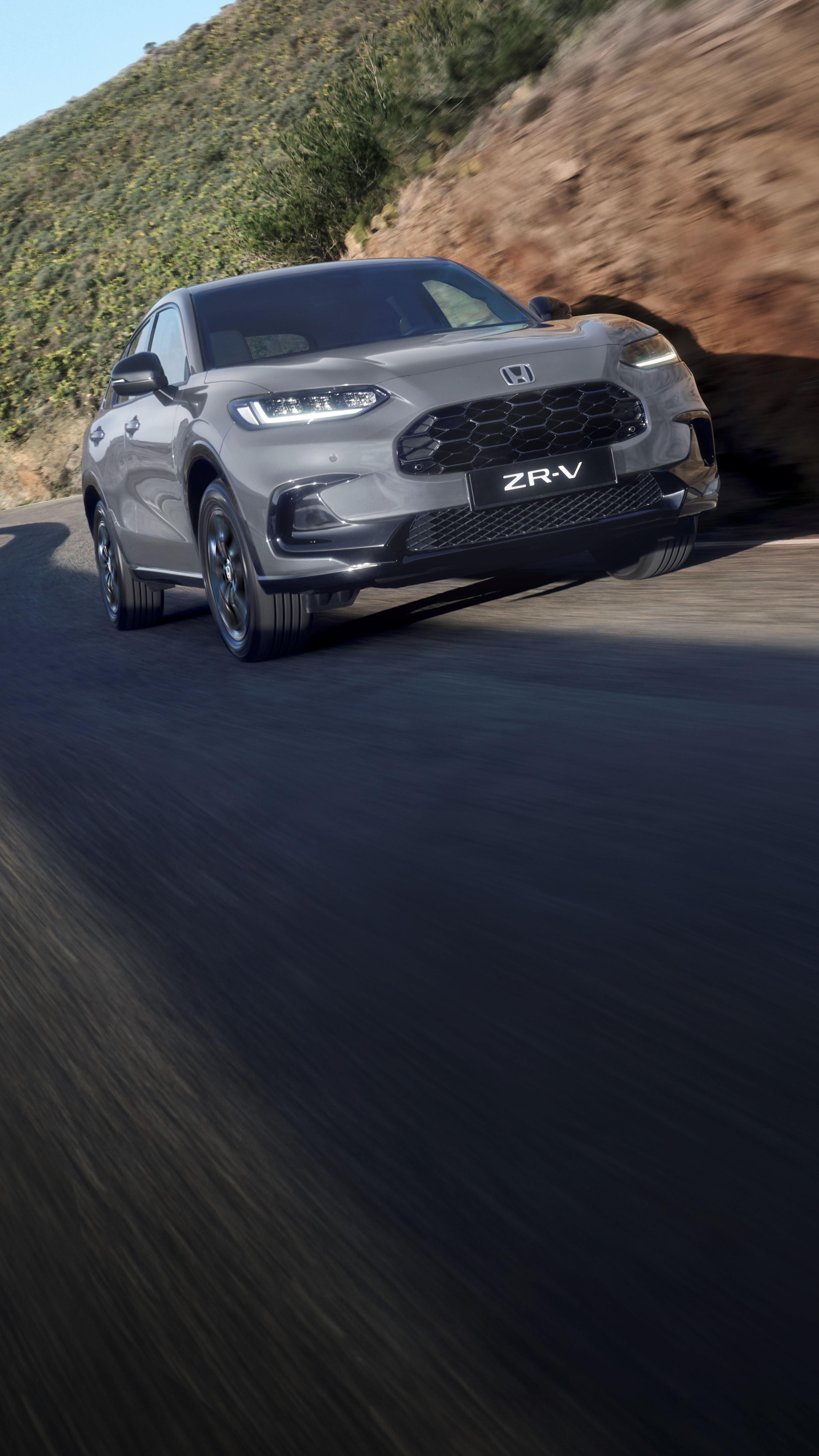Ein Honda ZR-V SUV fährt zügig bergauf auf einer kurvenreichen Bergstraße.