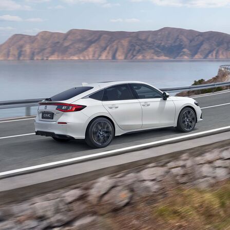 Honda Civic e:HEV auf einer Küstenstraße, Seitenansicht.