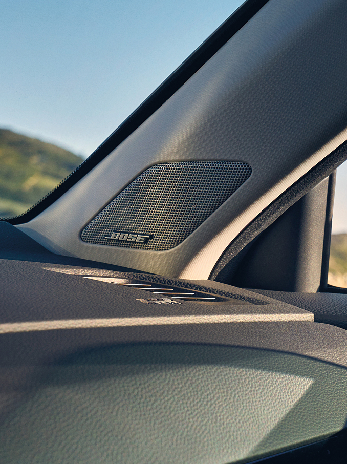  Eine Nahaufnahme eines Bose-Lautsprechers, der in die A-Säule eines Autos integriert ist und sich in der Nähe des Armaturenbretts und der Windschutzscheibe befindet.