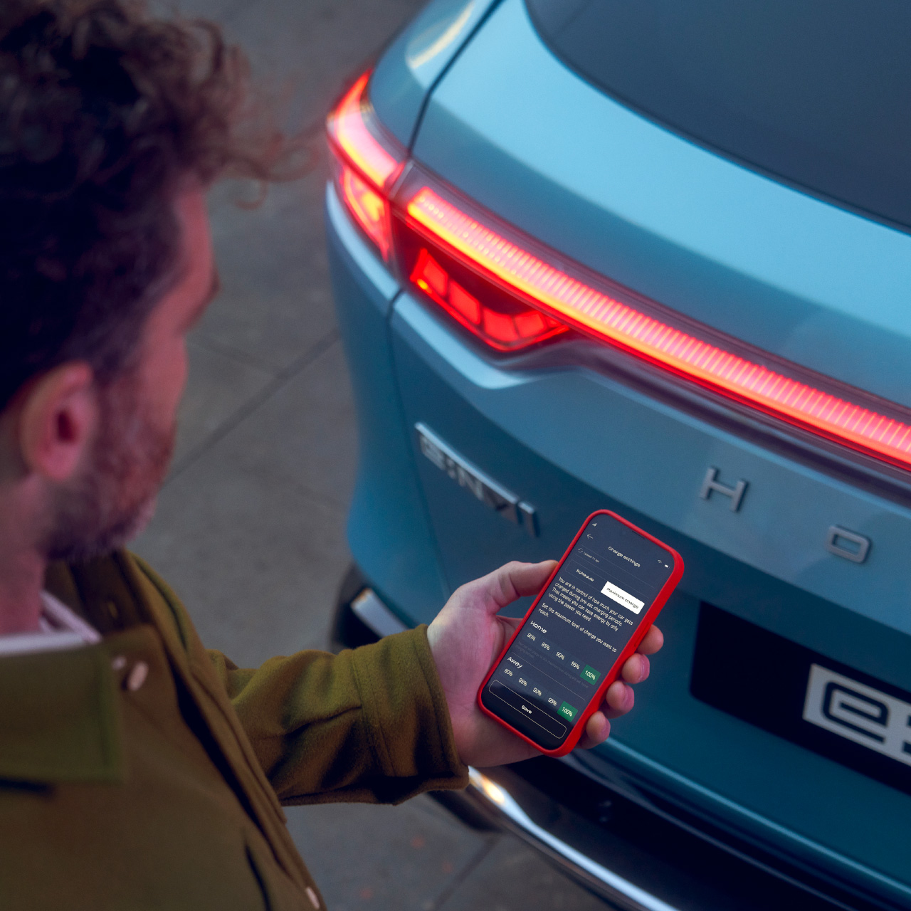 Mann, der die My Honda+ App verwendet, neben einem Honda e:Ny1.