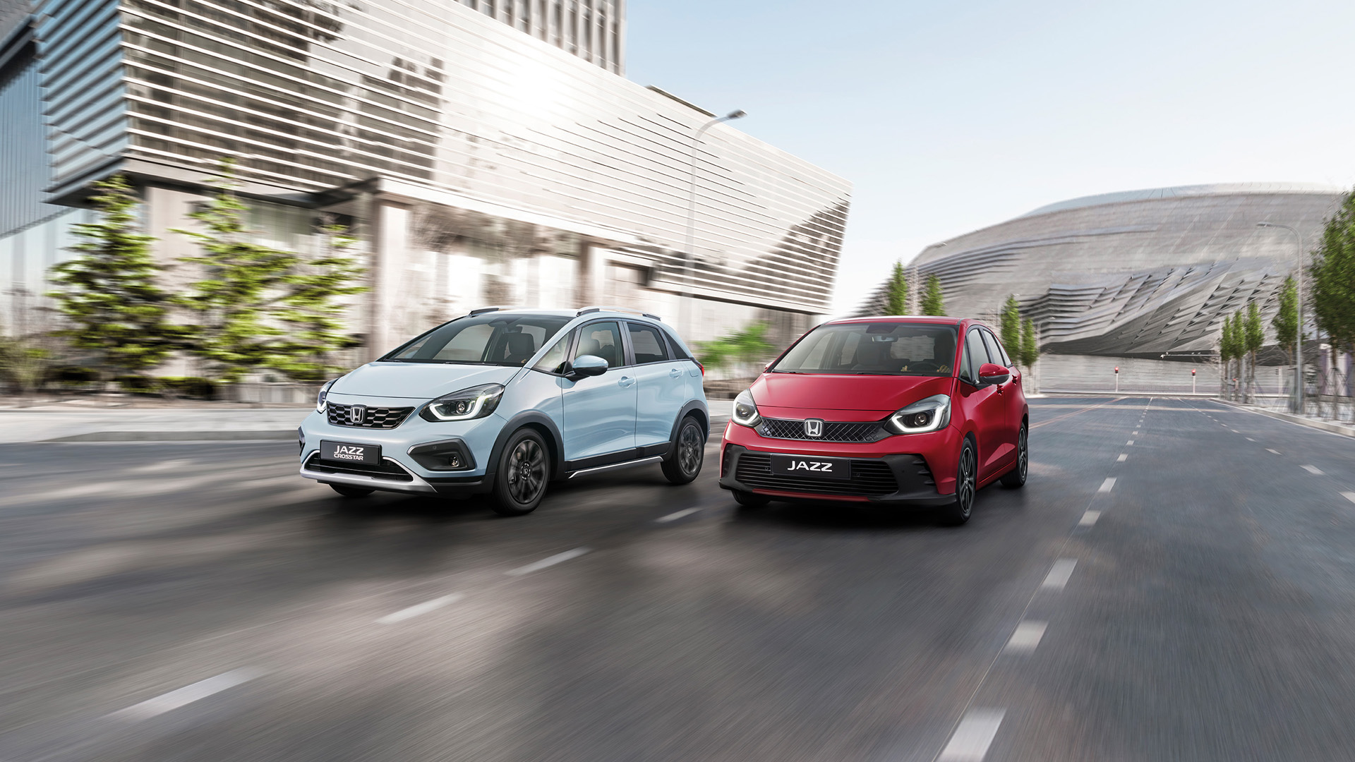 Ein Honda Jazz Hybrid und ein Honda Jazz Crosstar fahren nebeneinander in einer Stadt.