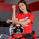 Frau in rotem Honda Top, die sich auf einen Honda Motorradhelm stützt.