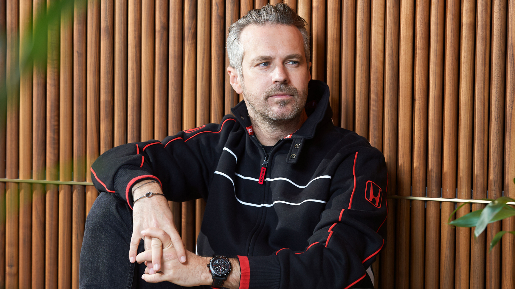 Mann mit Honda Racing Mütze und Jacke, der sich an den Mützenschirm tippt.