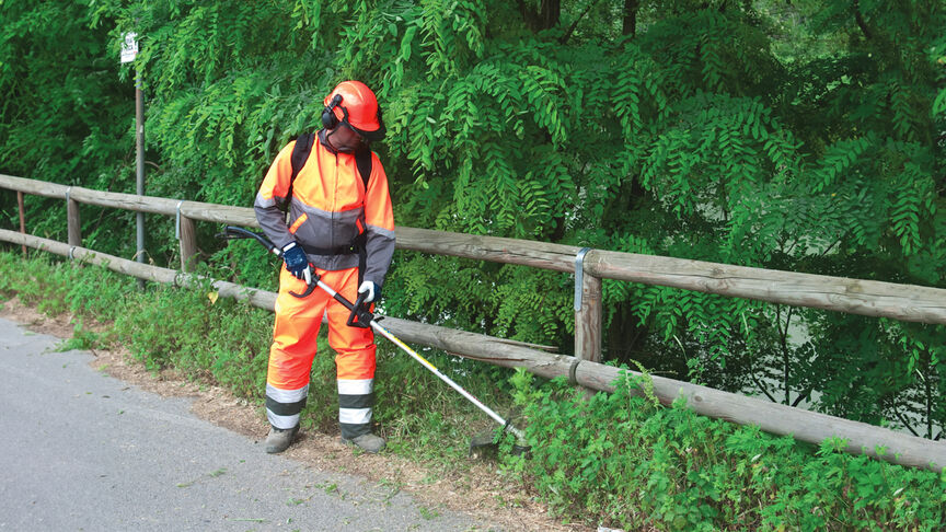 Model mit rückentragbarem Freischneider im Wald.