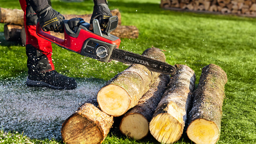 Nahaufnahme eines Modells, das mit einer Honda-Akku-Kettensäge Holz schneidet.