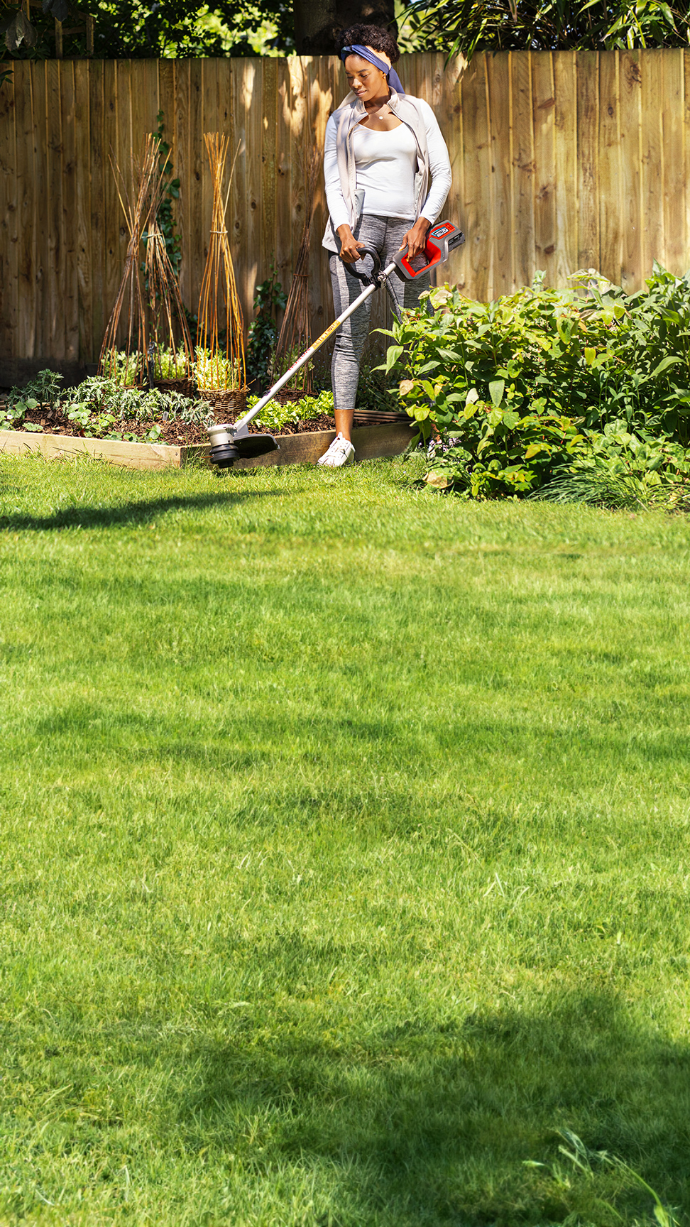 Model mit Honda Akku-Rasentrimmer im Garten.
