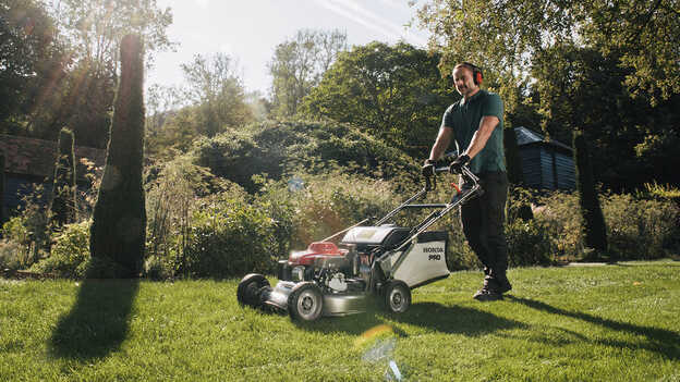 Ein Mann schiebt einen Honda HRH in einem Garten.