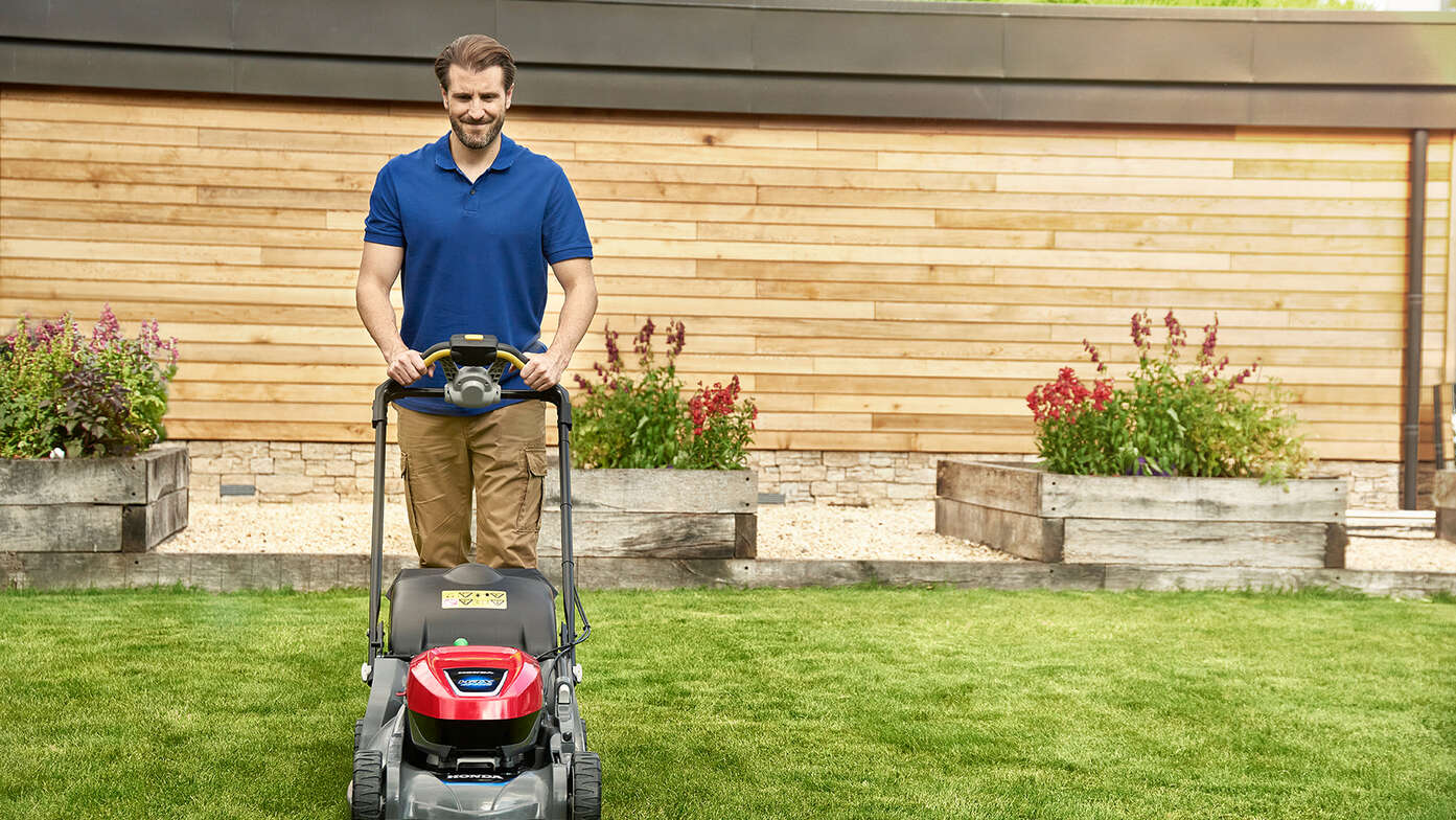 Ein Mann schiebt einen Honda HRX in einem Garten.