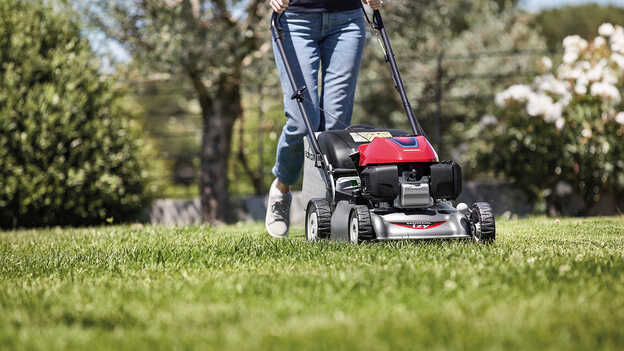 Honda IZY Rasenmäher, Seitenansicht mit einer Frau in einem Garten