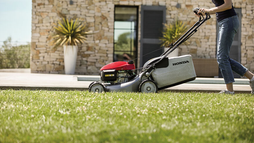 Honda IZY Rasenmäher, Seitenansicht mit einer Frau in einem Garten