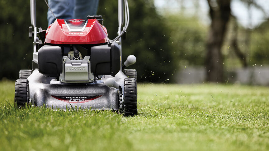 Honda IZY Rasenmäher, Seitenansicht mit einer Frau in einem Garten