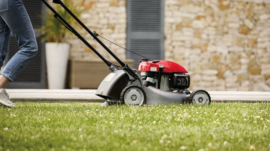 Honda IZY Rasenmäher, Seitenansicht mit einer Frau in einem Garten