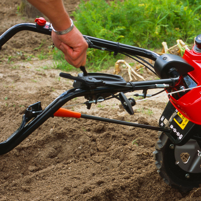 Nahaufnahme des Schaltkopfes einer Motorfräse, Gartenumgebung.