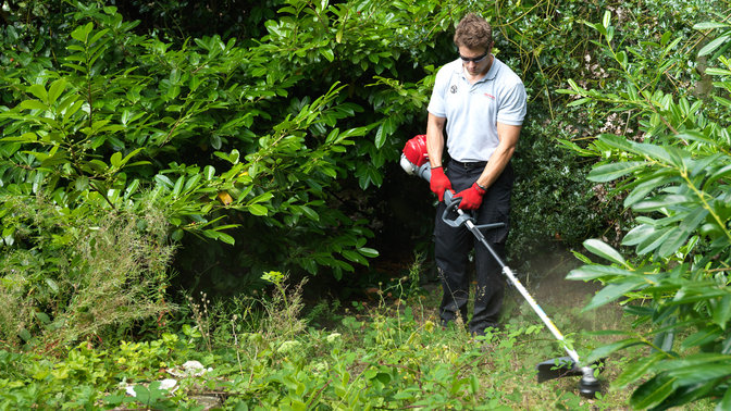 Honda Versatool mit Rasentrimmeraufsatz, Einsatz nach Modell, Gartenumgebung.