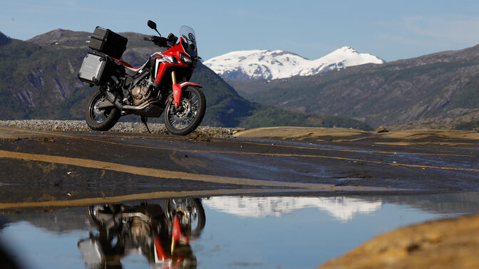 Africa Twin, abgestellt neben einem reißenden Fluss in Norwegen