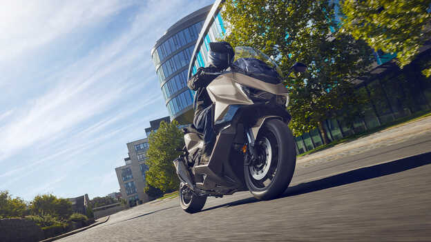 Dax 125 abgestellt, Dreiviertel-Heckansicht vor Meereshintergrund.