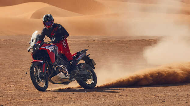Model mit einem CRF1100L Africa Twin-Motorrad in einer Wüste.