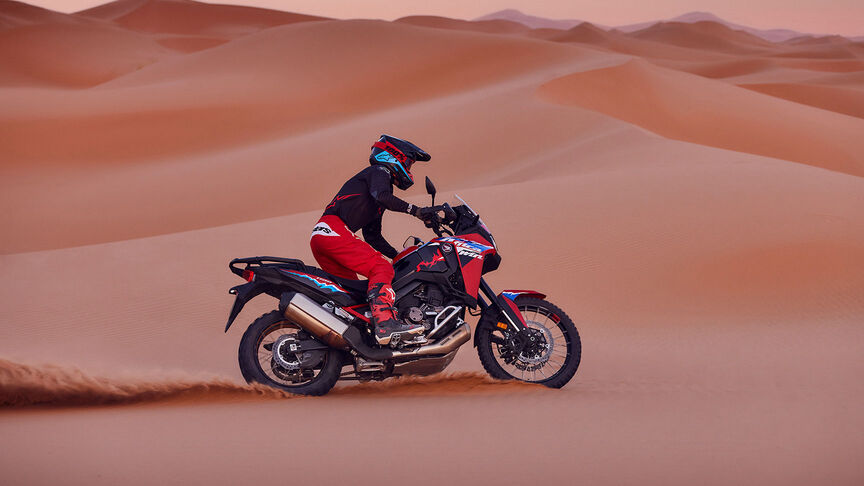 Model auf einem CRF1100L Africa Twin-Motorrad in einer Wüste.