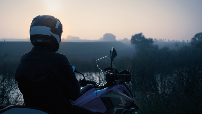 Honda NC750X mit Fahrer, stehend in ländlicher Umgebung.