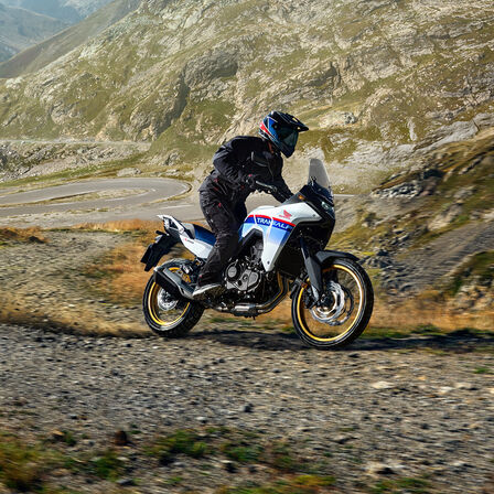 XL750 Transalp auf einer Schotterpiste vor einem Gebirge.