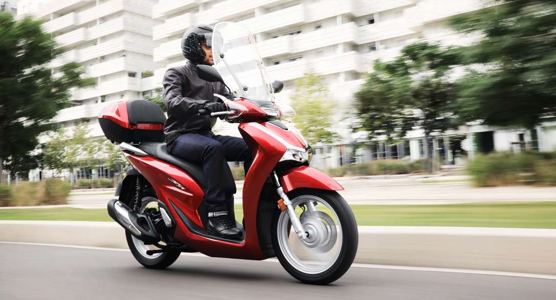 Honda SH125i, 3/4-Frontansicht rechts, mit Fahrer in der Stadt