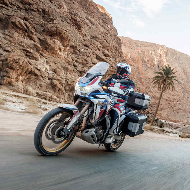 Africa Twin im Gelände mit Touring-Paket und Fahrer.