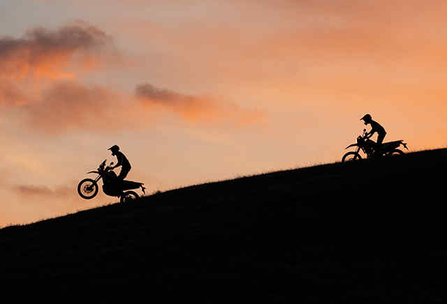 Zwei Honda 300-Motorräder bei der Fahrt bergab im Sonnenuntergang