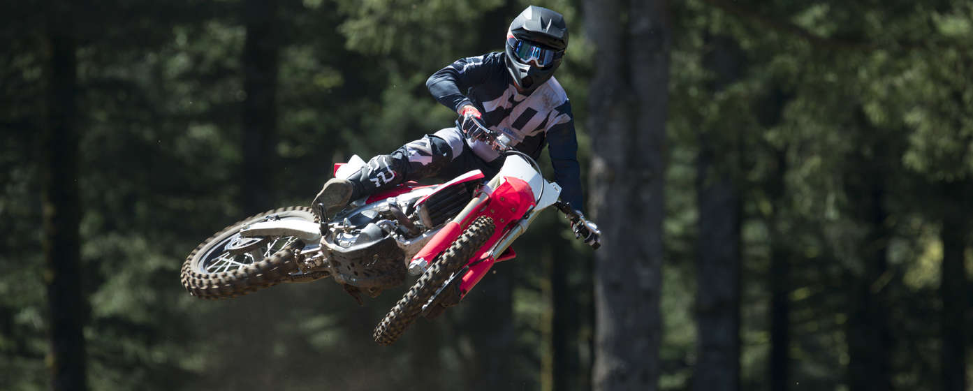 Front-facing CRF450R motorcycle jumping, with rider.