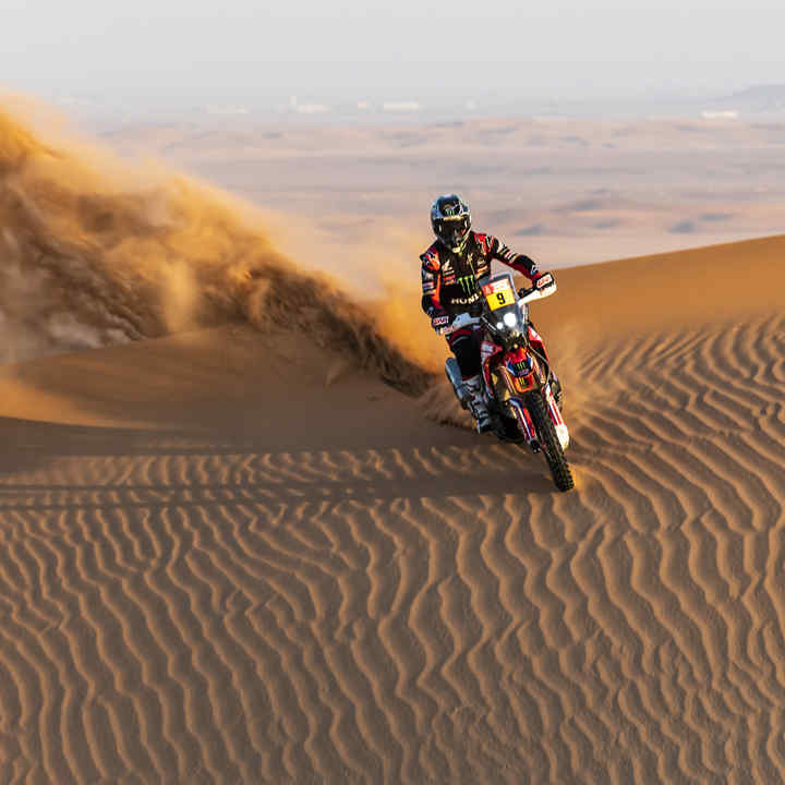 Honda Dakar-Fahrer in Wüstenlandschaft. 
