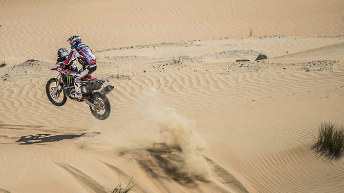 Dreiviertel-Heckansicht einer Honda CRF450 bei der Fahrt durch Sanddünen.