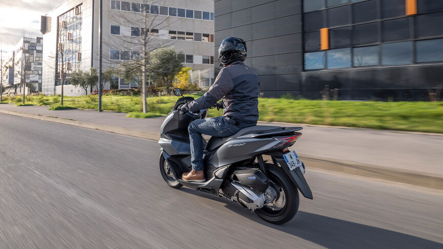 Honda PCX125 – ¾-Heckansicht in Bewegung mit Fahrer