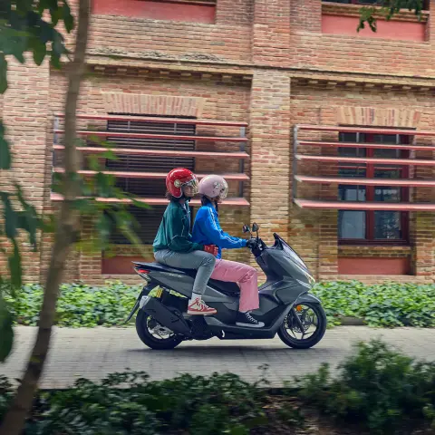 PCX125 mit Models in einer Stadt, Seitenansicht.