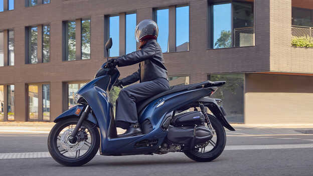 Fahrer auf dem Honda SH350 in der Stadt, Seitenansicht.