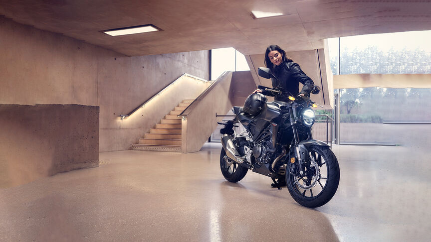 Honda CB300R, 3/4-Frontansicht mit Frau in einem Studio.