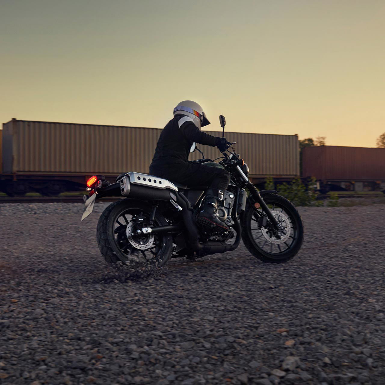 Model fährt Honda CL500 Motorrad in einer Lagerhalle.