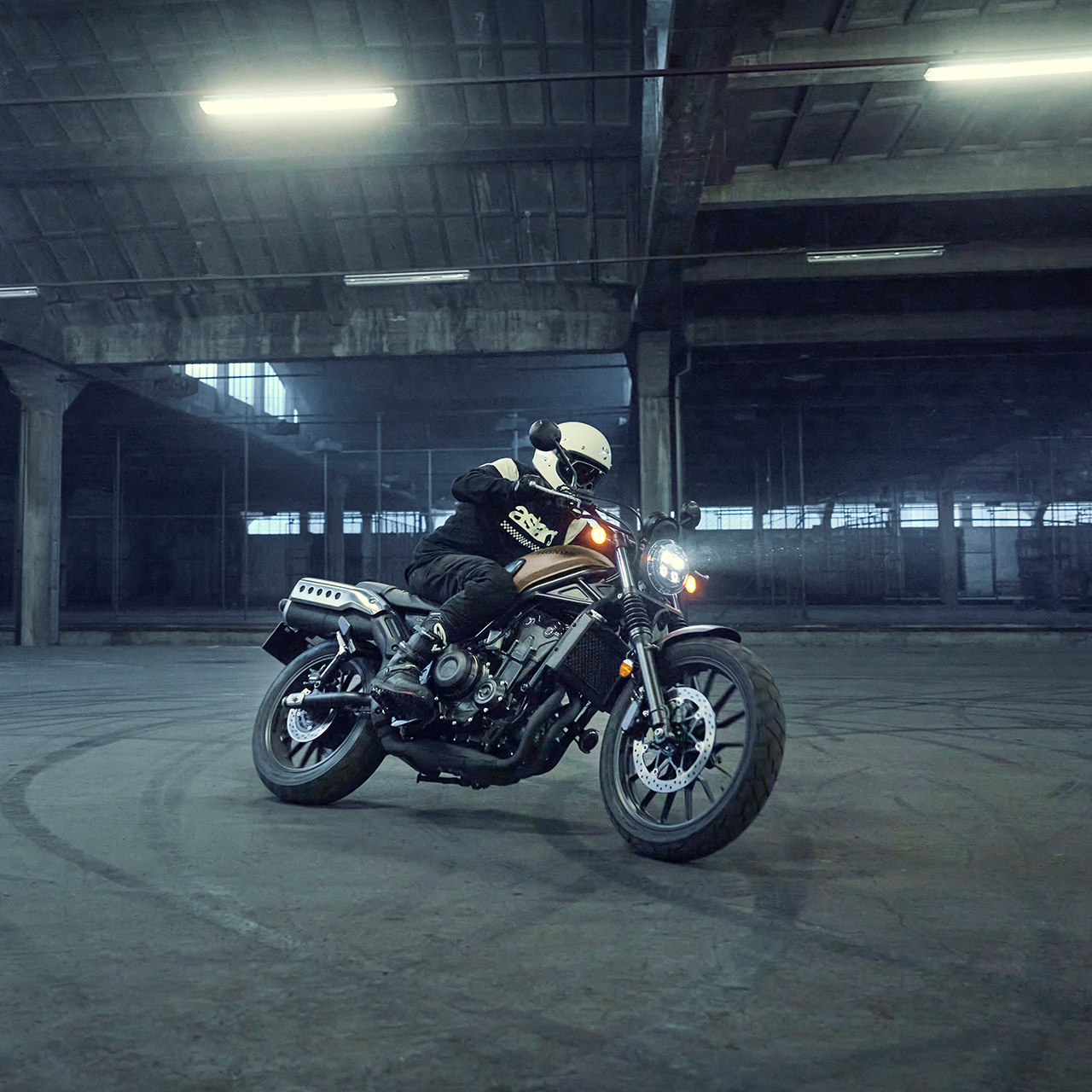 Model fährt Honda CL500 Motorrad auf einem Parkplatz.