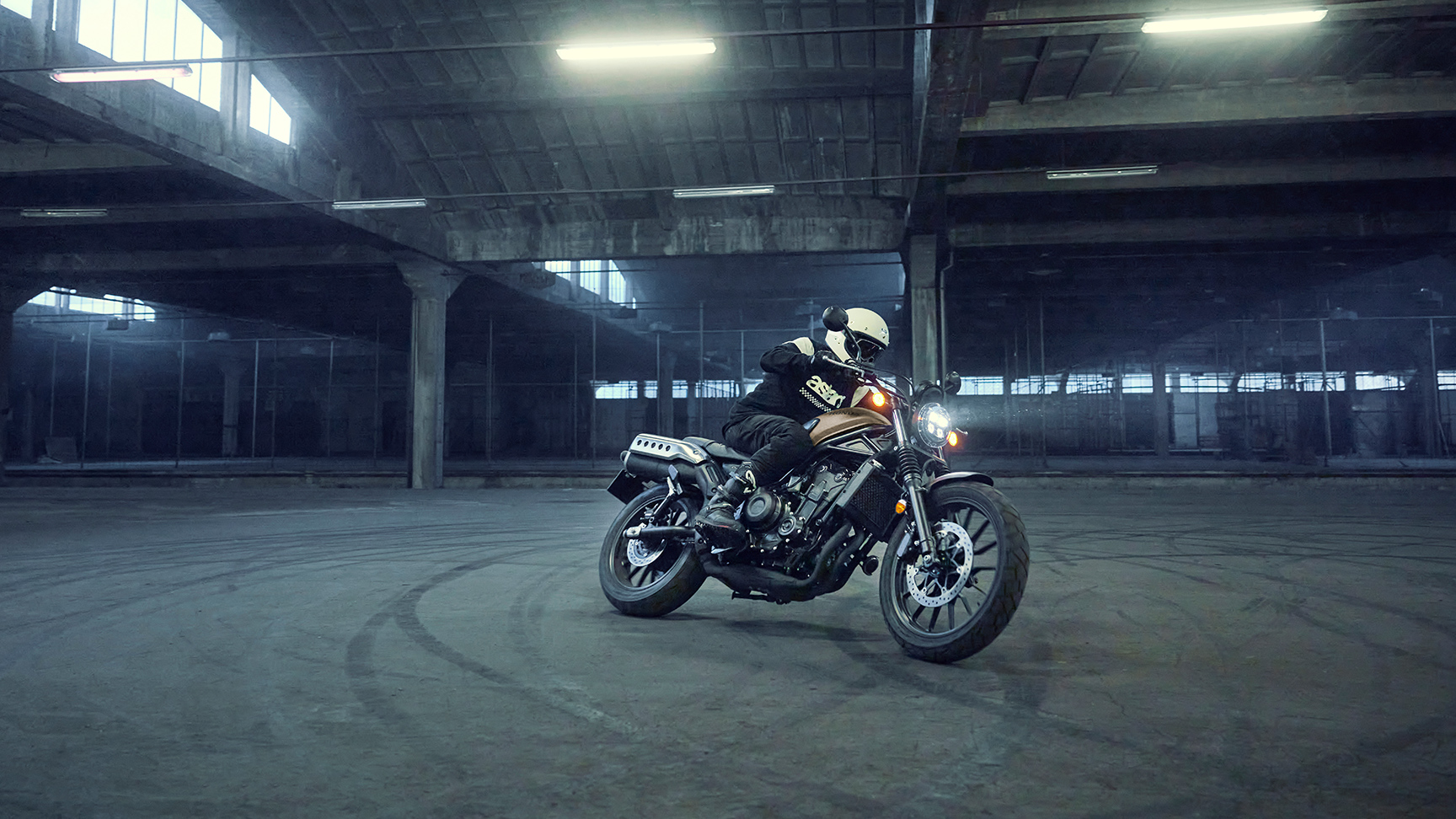Model fährt Honda CL500 Motorrad auf einem Parkplatz.