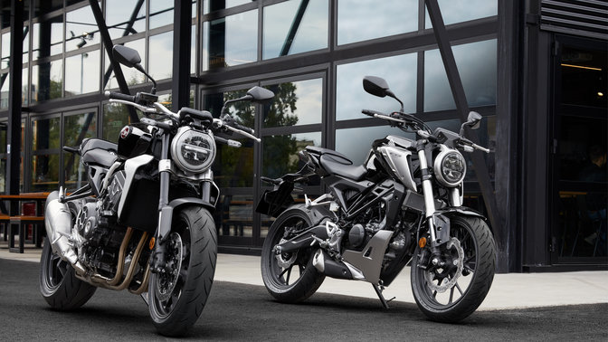 Honda CB1000R und CB125R, abgestellt auf einer Straße.