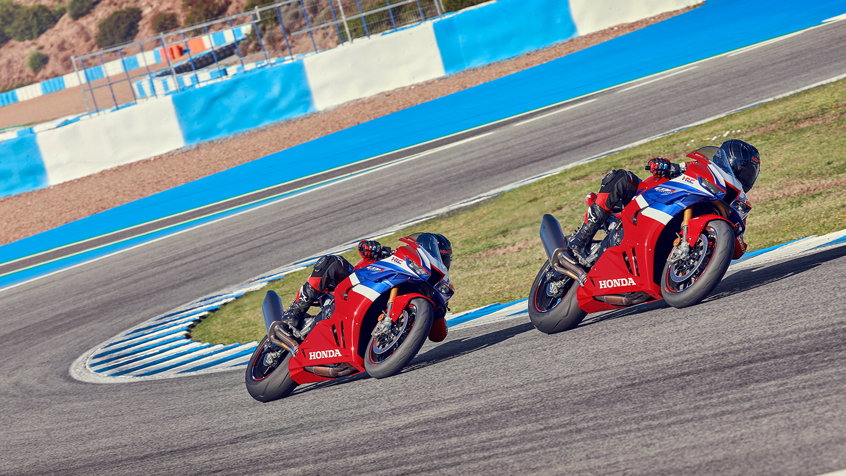 Honda CBR1000RR-R Fireblade auf der Rennstrecke mit zwei Fahrern in der Kurvenmitte